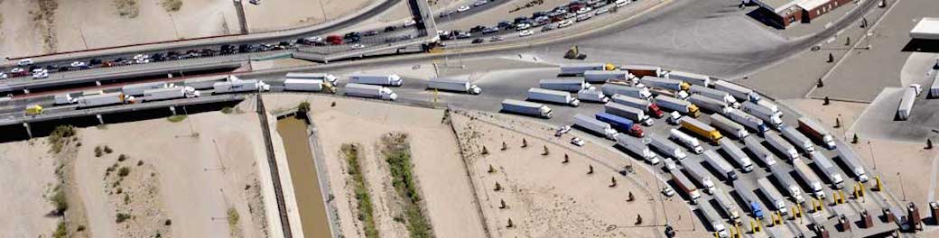 Medium view aerial photo of trucks queued at the U.S. - Mexico border.